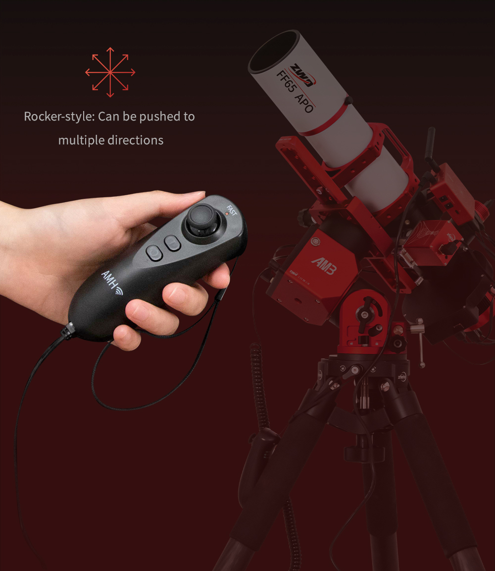 A hand is holding the AM3 Rocker Style Hand Controller, in the background the mount sits on a pier with a refracting telescope.